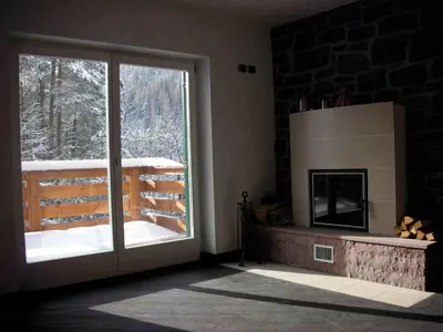 a living room with a fireplace and a sliding glass door at Chalet Villa Bianca in Tesero