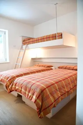 a bedroom with two beds and a ladder at Chalet Villa Bianca in Tesero