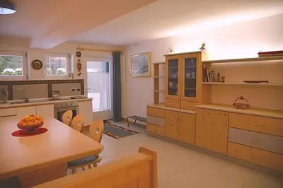 a kitchen with wooden cabinets and a table and chairs at Chalet Villa Bianca in Tesero