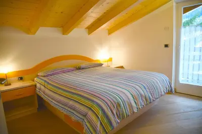 a bedroom with a bed and a desk and a window at Chalet Villa Bianca in Tesero