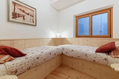 two beds in a room with a window at Villa Olimpia - Stayincortina in Cortina dʼAmpezzo