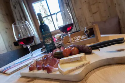 a wooden cutting board with wine glasses and meat and cheese at Agriturismo Lüch de Vanc in San Martino in Badia