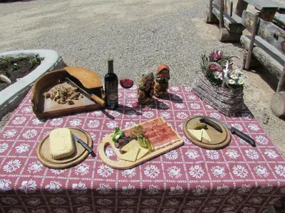 a picnic table with food and a bottle of wine at Agriturismo Lüch de Vanc in San Martino in Badia