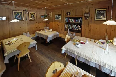 a dining room with two tables and a book shelf at Agriturismo Lüch de Vanc in San Martino in Badia