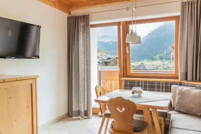 a living room with a table and a large window at Apartments Ansciuda in Ortisei