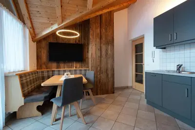 a kitchen with a table and a tv on the wall at Apartments Ansciuda in Ortisei