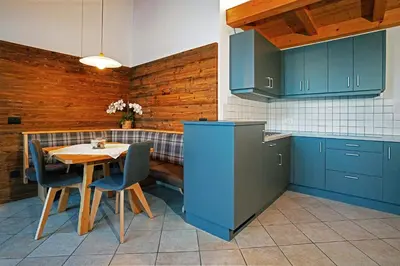 a kitchen with blue cabinets and a table with chairs at Apartments Ansciuda in Ortisei