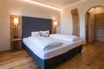 a bedroom with a large bed with white sheets and pillows at Hotel Garni Vigilhof in Lana