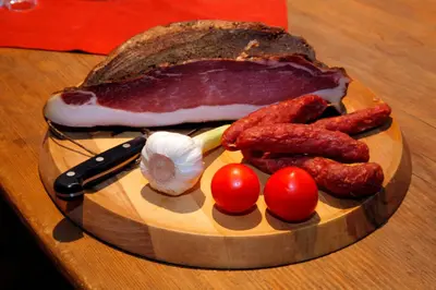 a plate of food with sausage tomatoes and a loaf of bread at Hotel Garni Vigilhof in Lana