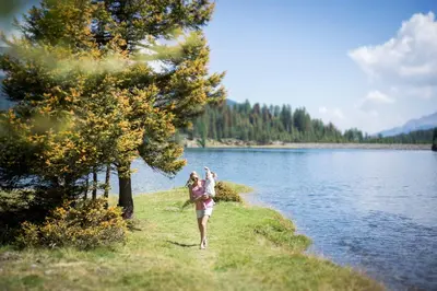 a woman walking along the shore of a lake at Hotel Garni Vigilhof in Lana