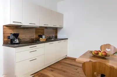 a kitchen with white cabinets and a wooden table at Praitladhof in Lana