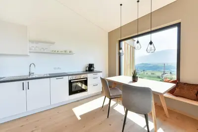 a kitchen with a table and chairs and a large window at Villa Montis Exclusive Holiday Apartments in Eppan with Spectacular Views of Dolomites and Bolzano Area in Appiano sulla Strada del Vino