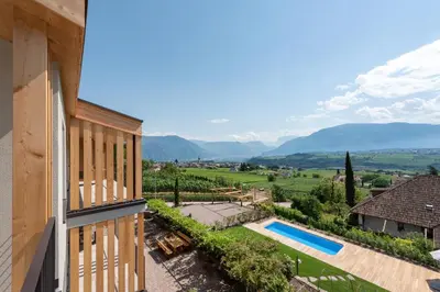 a view of a villa with a swimming pool and mountains at Villa Montis Exclusive Holiday Apartments in Eppan with Spectacular Views of Dolomites and Bolzano Area in Appiano sulla Strada del Vino