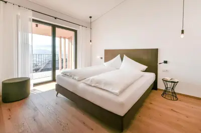 a bedroom with a large bed and a large window at Villa Montis Exclusive Holiday Apartments in Eppan with Spectacular Views of Dolomites and Bolzano Area in Appiano sulla Strada del Vino