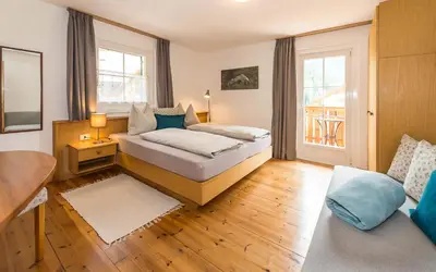 a bedroom with a bed and a table and a couch at Haus Claudia B&B in Nova Levante
