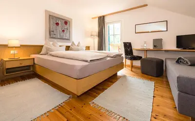 a bedroom with a bed and a living room with a couch at Haus Claudia B&B in Nova Levante