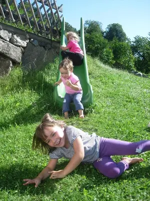 two children playing on a slide in the grass at Malsethhof in Villandro
