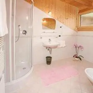 a white bathroom with a sink and a shower at Tinahof in Selva di Val Gardena