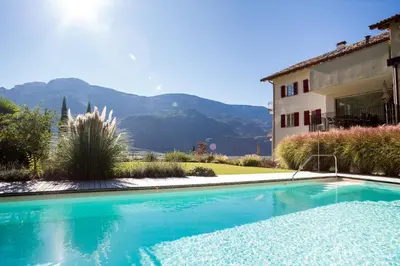 a swimming pool in front of a house with a mountain at Ferienwohnungen Hochbrunner in Terlano