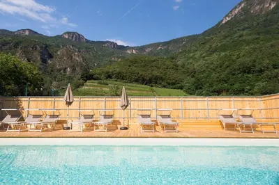a group of chairs and umbrellas next to a swimming pool at Ferienwohnungen Hochbrunner in Terlano