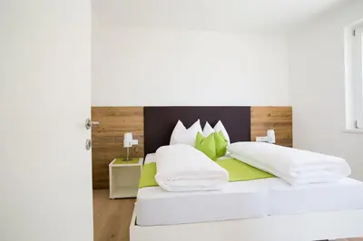a bedroom with a white bed with green pillows at Ferienwohnungen Hochbrunner in Terlano