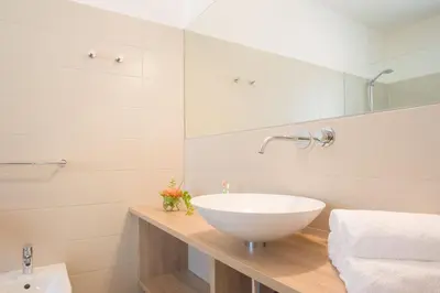 a white bathroom with a sink and a mirror at Ferienwohnungen Hochbrunner in Terlano