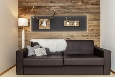a leather couch in a living room with a wooden wall at Apartment Wieser Eppan in Appiano sulla Strada del Vino
