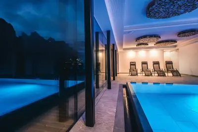 a swimming pool in a building with chairs at Lüch de Costa in Colfosco