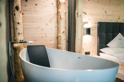 a bath tub in a room with a bedroom at Lüch de Costa in Colfosco