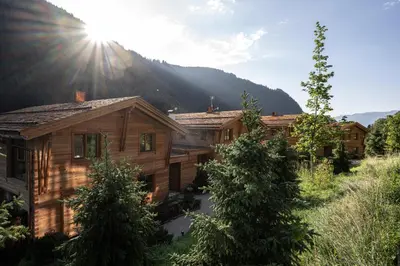 a row of wooden houses in front of a mountain at Valsegg Chalets Südtirol - luxury and private hideaway in Valles