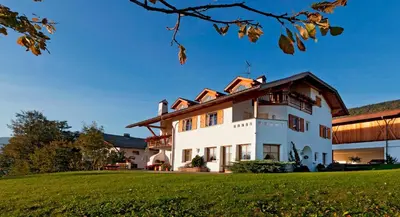 a large white house with a green lawn at Appartement Huber in Brunico