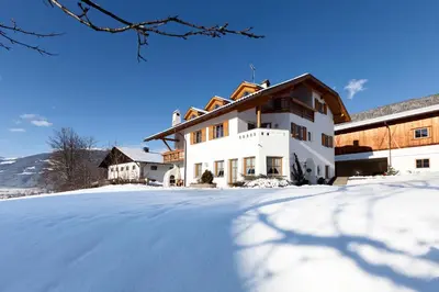 a building with snow on the ground in front of it at Appartement Huber in Brunico
