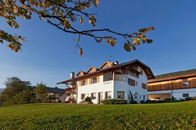 a large white house with a green lawn at Appartement Huber in Brunico