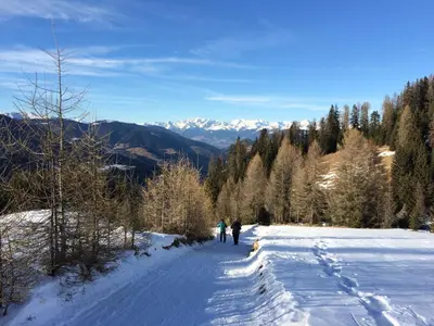 two people are walking down a snow covered road at Ciasa Orzun in San Vigilio Di Marebbe