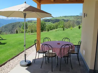 a patio with a table and chairs and an umbrella at Gasserhof Chalets in Meltina