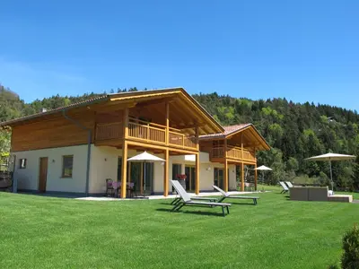 a house with chairs and umbrellas in the grass at Gasserhof Chalets in Meltina
