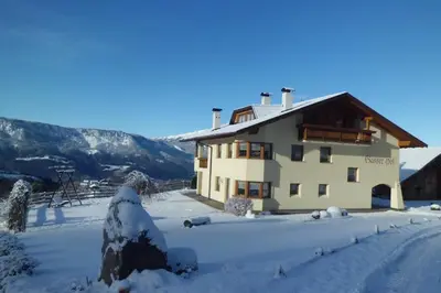 a house in the snow with mountains in the background at Gasserhof Chalets in Meltina