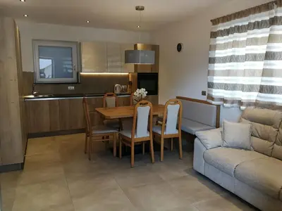 a kitchen and living room with a table and a couch at Fiemme Home Mountain Apartment in Tesero