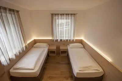 a room with two beds and a window at Fiemme Home Mountain Apartment in Tesero