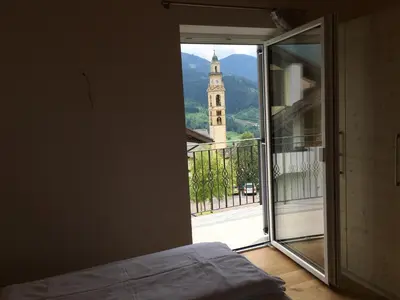 a bedroom with a view of a tower and a church at Fiemme Home Mountain Apartment in Tesero
