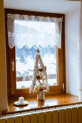 a christmas tree in a window with a christmas ornament at COL DE RIF Appartamento Storico nelle Dolomiti in Falcade