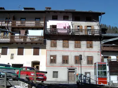 a building with balconies and a red truck parked in front of it at COL DE RIF Appartamento Storico nelle Dolomiti in Falcade