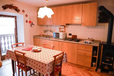 a kitchen with a table with chairs and a microwave at COL DE RIF Piccolo Appartamento Storico Dolomiti in Falcade