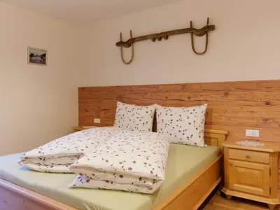 a bed with a wooden headboard and pillows on it at Niederhof in Parcines