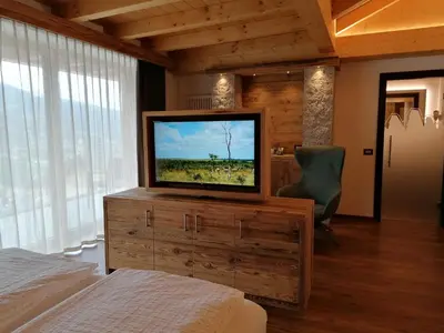 a bedroom with a flat screen tv on a dresser at DOLOMITES B&B - Suites, Apartments and SPA in Tesero