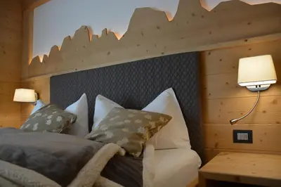a bedroom with a bed with a wooden headboard at DOLOMITES B&B - Suites, Apartments and SPA in Tesero