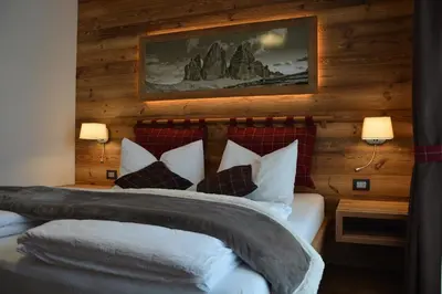 a bedroom with a bed with white pillows at DOLOMITES B&B - Suites, Apartments and SPA in Tesero