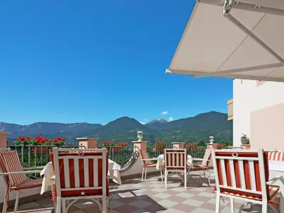 a patio with chairs and tables with mountains in the background at Apartment Pienzenau by Interhome in Postal