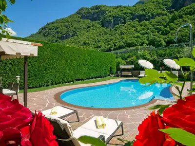 a swimming pool with chairs and a mountain in the background at Apartment Schöneck by Interhome in Postal