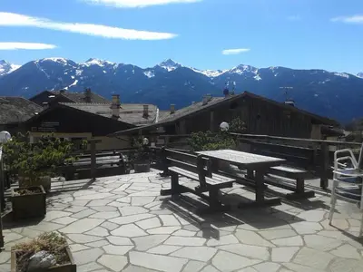 a picnic table on a patio with mountains in the background at Albergo Pensione Serenetta in Varena